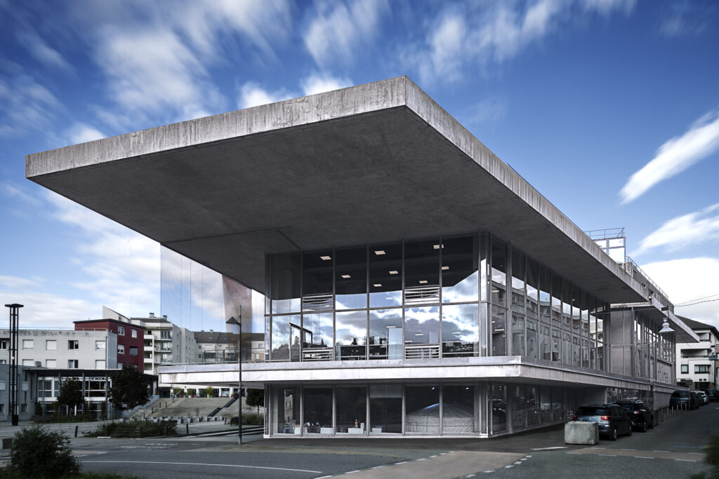 Photographie d'architecture en Haute-Savoie. D'un bâtiment contemporain aux larges baies vitrées et portes à faux de dalles de béton. Ce bâtiment et un pôle multiculturel situé à Cran-Gevrier.