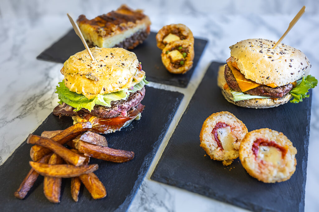 Photographie culinaire, des burgers et des frites posés sur des ardoises.