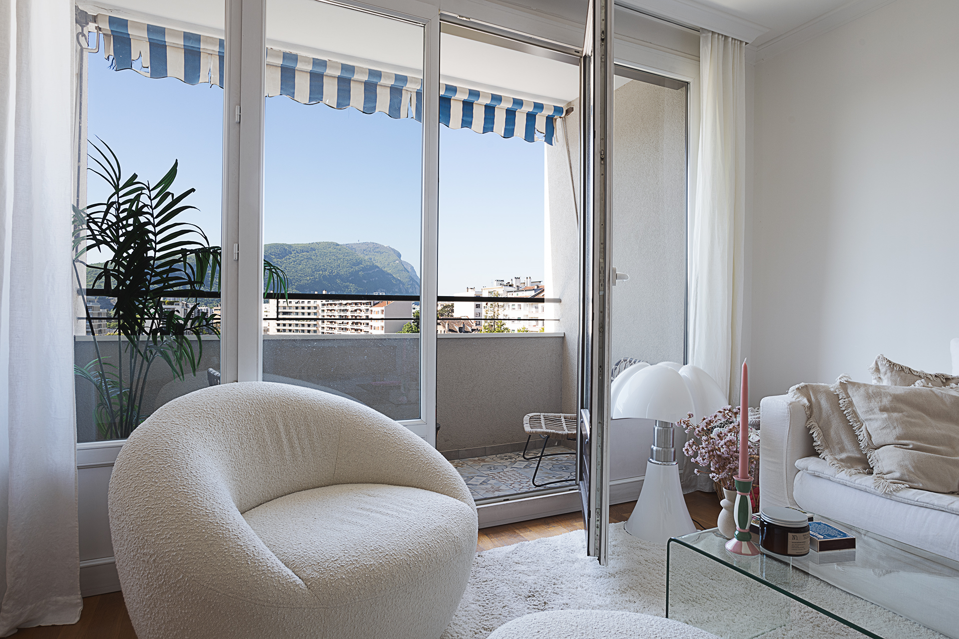 Photographie immobilières d'un appartement en haute -Savoie. A travers la baie vitré du salon on peut voir par le balcon le mont Salève.