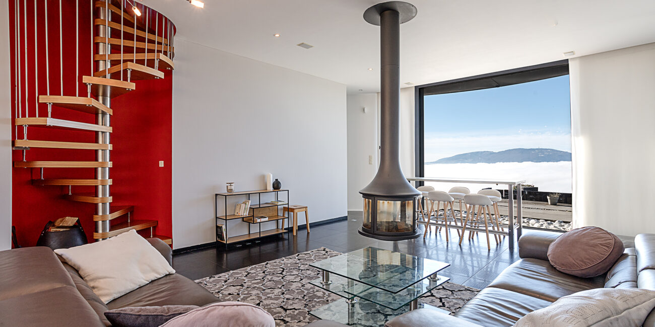 Photographie immobilière d'une maison situé sur les hauteurs du bassin Lémanique. Le salon et sa vue sur les montagnes.